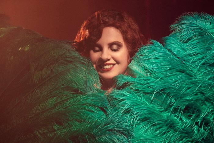 Portrait au sourire parmi des plumes vertes